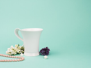 The elegant white Cup, the lilac and the pearls on turquoise background.