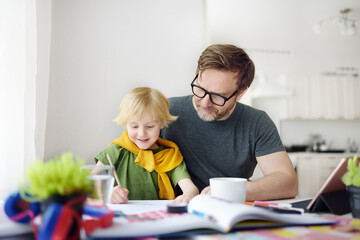 Father helping child do his homework at home. Homeschooling, distance learning, online studying, remote education for kids during quarantine is a problems for parents. Tutor teaching boy with ADHD.