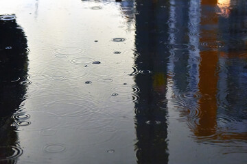 Drops of rain bubbling in a puddle with the reflection of light