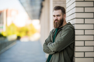Stylish young bearded guy in casual clothes walking in the street outdoors