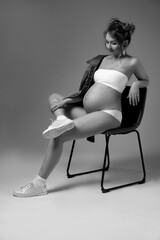 Black and white studio photo  of a pregnant woman.  Pregnancy and expecting a baby concept