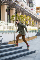 Young hipster bearded man in hurry run stairs on the street
