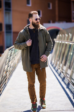 Cheerful bearded hipster man walking on the street bringe