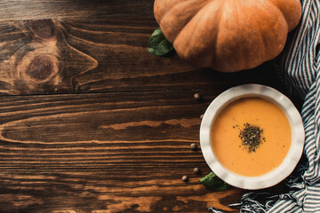 Pumpkin and carrot cream soup on dark wooden background. Top view.