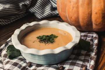 Pumpkin and carrot cream soup on the dark wooden table. Healthy food.