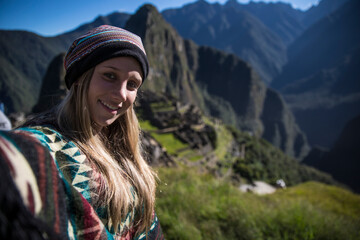 Blonde young woman smiling at the camera in machu picchu in a selfie - obrazy, fototapety, plakaty