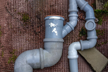 Sewer pipes of gray color and of different sizes, turning into each other, located on the street,...