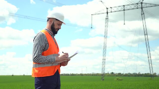 Engineer working near transmission lines. Electrical engineer checks high voltage lines. Transmission towers
