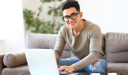 Friendly male freelancer using laptop on sofa.