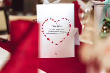 Welcome card with red heart symbol standing on table. wedding concept