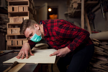 Fototapeta na wymiar Carpenter at work in workshop with mask on face