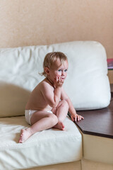Cute baby girl in diapers lying on bed