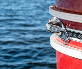 Stainless steel light on the front corner of a red pontoon drifting on a lake.