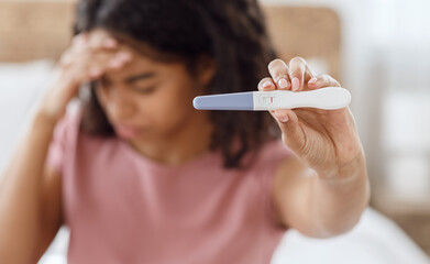 Depressed black lady holding negative pregnancy test