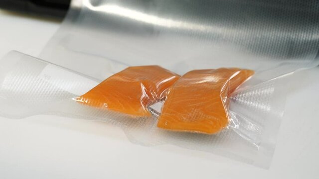 Raw fish fillets vacuum sealed in the kitchen. Packing fresh salmon steak for storing.