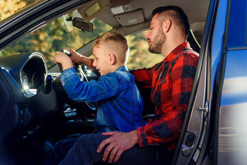 handsome father pointing on something while teaching teen son driving car