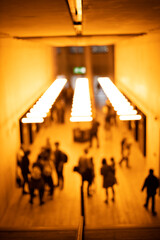 Silhouettes of people walking under orange lights