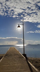 wooden pier going out to sea to the horizon and lantern against the background of the sun glare