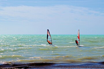 boys who practice windsurfing during a very windy day in the sea of Livorno in Tuscany in Italy