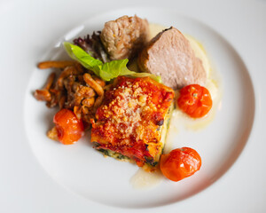 vegetable lasagne and veal beef on white plate