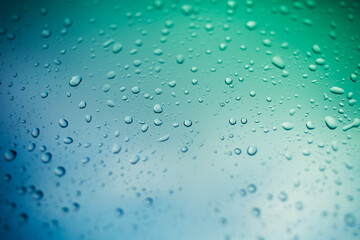 water drops on glass window, green and blue background