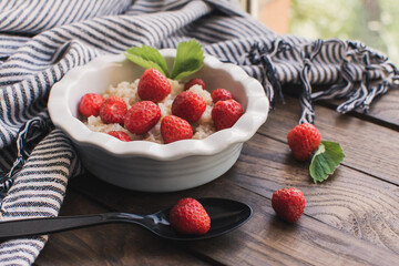 Breakfast. Tasty oatmeal with berries. Healthy breakfast ingredients. Oat granola in bowl with strawberry and mint. Granola for breakfast with berries.