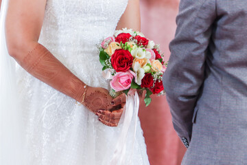 Indian couple's hands holding a beautiful wedding bouquet red and pink roses