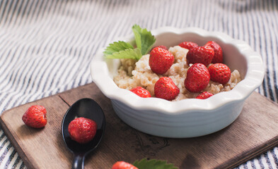 Breakfast. Tasty oatmeal with berries. Healthy breakfast ingredients. Oat granola in bowl with strawberry and mint. Granola for breakfast with berries.