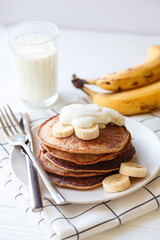 Fototapeta na wymiar Banana pancakes with whole wheat flour on white background, bananas, yogurt and glass of milk. Healthy breakfast, breakfast concept, morning concept