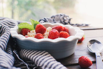 Breakfast. Tasty oatmeal with berries. Healthy breakfast ingredients. Oat granola in bowl with strawberry and mint. Granola for breakfast with berries.