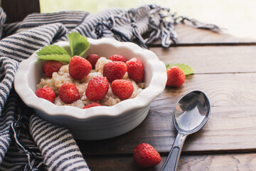 Breakfast. Tasty oatmeal with berries. Healthy breakfast ingredients. Oat granola in bowl with strawberry and mint. Granola for breakfast with berries.
