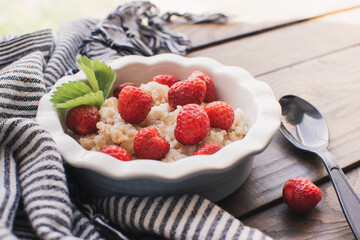 Breakfast. Tasty oatmeal with berries. Healthy breakfast ingredients. Oat granola in bowl with strawberry and mint. Granola for breakfast with berries.