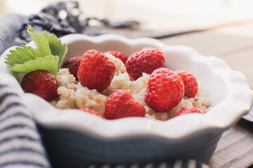 Breakfast. Tasty oatmeal with berries. Healthy breakfast ingredients. Oat granola in bowl with strawberry and mint. Granola for breakfast with berries.