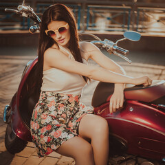 Portrait of a young brunette in a colorful dress and sunglasses in the summer in the city on a...