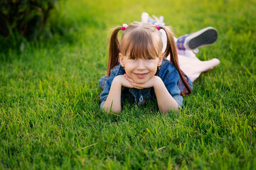 Fototapeta premium happy smiling six year old girl lies on the grass in the park