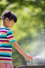真夏の公園で水遊びをしている可愛い子供