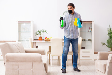 Young male contractor cleaning the house in coronavirus concept