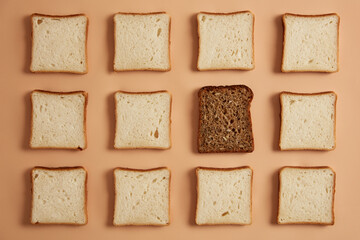 Set of white and wholegrain bread slices on light beige background. Rectangular pieces of bread made of organic flour, one is dark prepared for toasting. Top view from above, flat lay. Pastry food.