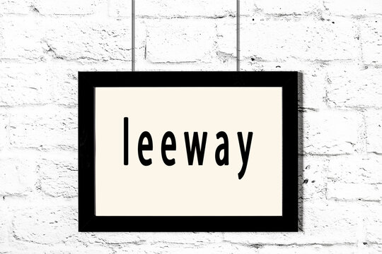 Black frame hanging on white brick wall with inscription leeway