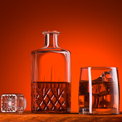 A glass of whiskey or cognac, a decanter and ice cubes, close-up on a wooden table.