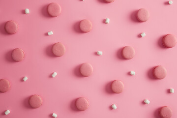 French sweet macaroons of round shape with white marshmallow on pink background. Yummy traditional French dessert. Macarons in one color. Delicious cookies as treat for holiday. Junk food concept