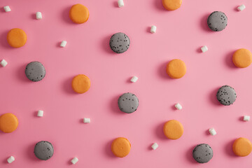 Set of orange and coffee flavored macaroons with appetizing marshmallow isolated on pink background. Small french cakes. Delicious homemade cookies for sweet tooth. View from above. Macarons banner