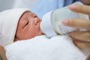 little newborn baby sucking milk in bottle