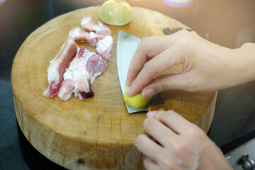 Cutting pork on a chopping block. Knife and Raw Pork Meat on Wood Cutting Board or Chopping Block. Use lime to clean up a knife.