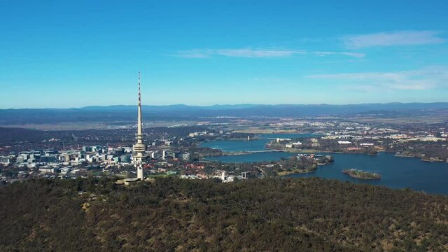 Aerial flyby of Telstra Tower in Canberra, the capital of Australia, showing a panoramic view of Lake Burley Griffin and surrounding landmarks and countryside       