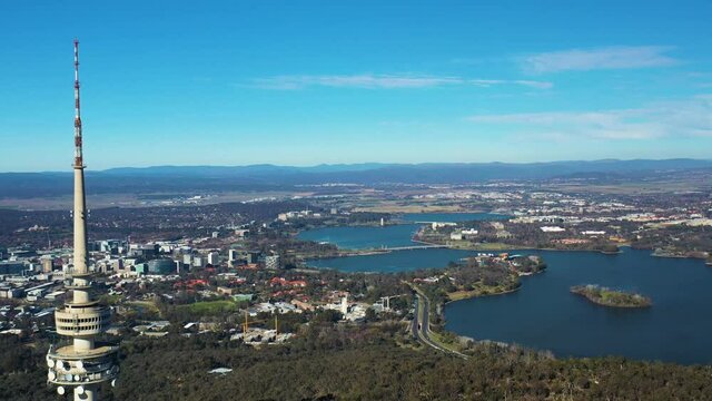 Aerial flyby of Telstra Tower in Canberra, the capital of Australia, showing a panoramic view of Lake Burley Griffin and surrounding landmarks and countryside       