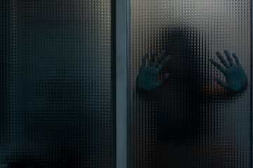 Woman behind textured glass. Hands resting on the glass. Dramatic theme photography. Terror,...