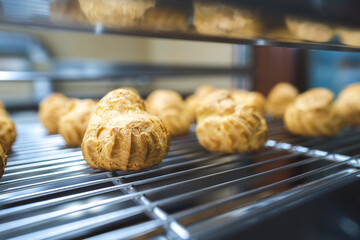 Close up choux baked home made  fresh crispy eclairs and profiteroles. Making desserts and sweets on an industrial scale, industry, background.Choux is a traditional french dessert.