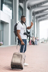 Portrait Of Cheerful African Tourist With Luggage Posing Outside Of Airport