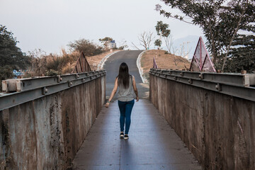 young woman crossing a bridge